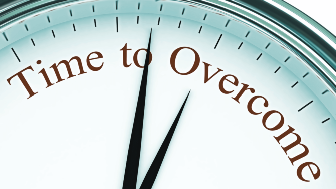 A zoomed up close clock face with the words "time to overcome" and both hands pointing to the words.